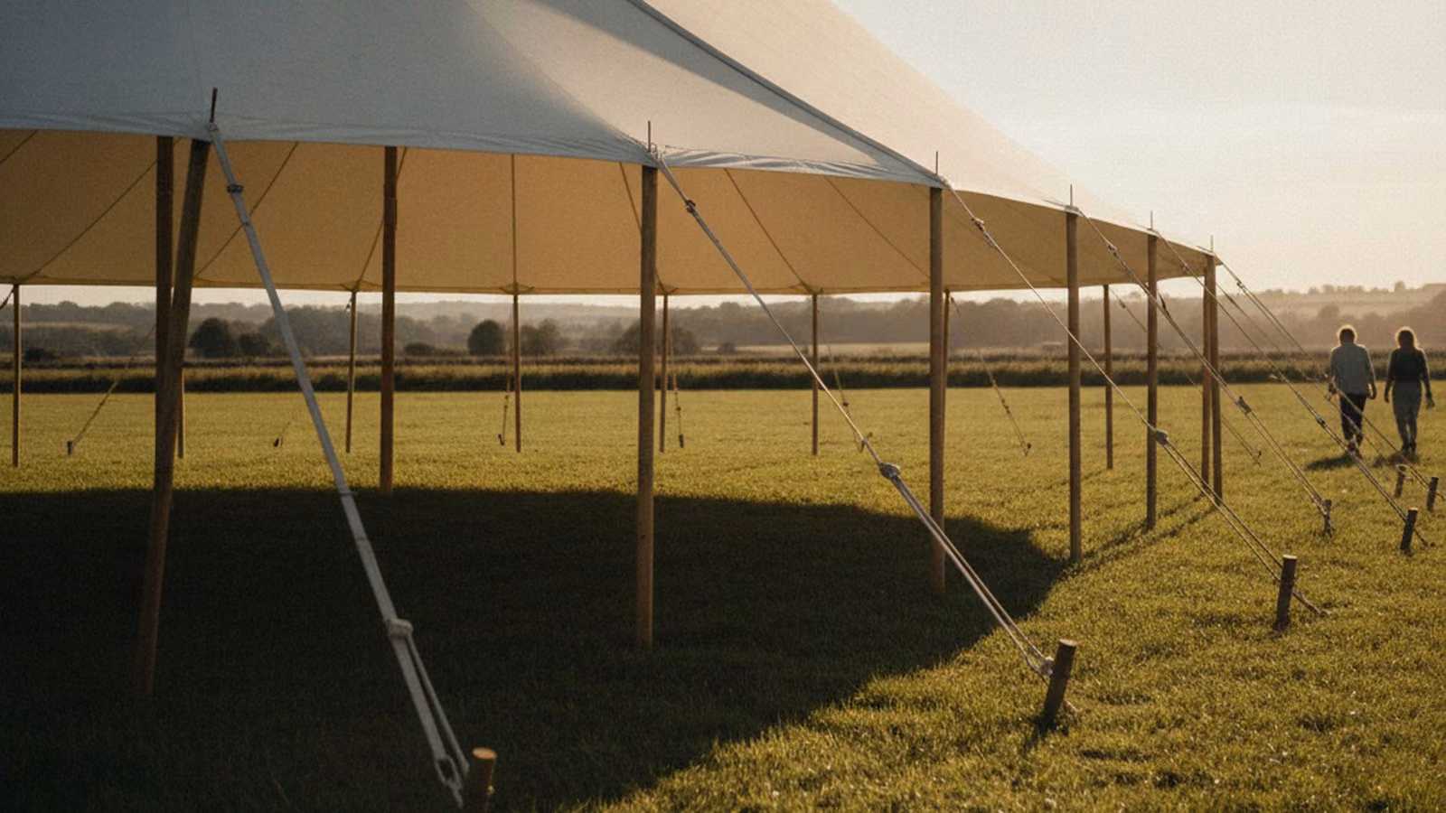 Traditional white peg and pole canvas event tent on a grass field